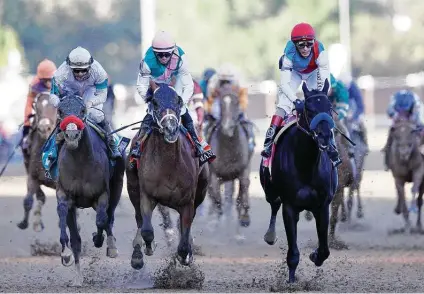  ?? Sarah Stier / Getty Images ?? Medina Spirit, ridden by jockey John Velazquez at right, crosses the finish line to win the 147th running of the Kentucky Derby on Saturday at Churchill Downs in Louisville, Ky. The race, which normally brings in 150,000, had an announced attendance of 51,838.
