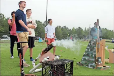  ?? Photos by Spencer Lahr, Rome News-Tribune ?? ABOVE: Rome High honors physics students Holden Young (left) and Bill Elder track a tennis ball they blasted out of their compressed air cannon Friday. The burst of air sent the ball roughly 85 yards across Rome’s practice football field.
LEFT:...