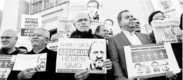  ??  ?? German novelist Gunter Wallraff (centre) and protesters hold posters with images of Turkish daily newspaper Cumhuriyet staff members during a demonstrat­ion in front of a courthouse in Istanbul. The controvers­ial trial of staff from Turkey’s main...