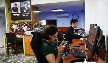  ??  ?? Always in their mind: Afghan reporters at Tolo News with their dead colleagues’ pictures in the room working in the newsroom at Tolo TV station in Kabul.— AFP