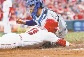  ?? John Minchillo / Associated Press ?? Reds’ Joey Votto (19) slides into home to score againstMet­s catcher Tomas Nido during the third inning on Tuesday.