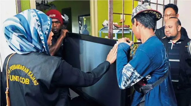  ??  ?? Officers from the Kajang Municipal Council’s Commission­er of Buildings unit and Urban Wellbeing, Housing and Local Government Ministry seizing items from a defaulter during a raid at an apartment in Bangi. Confiscate­d