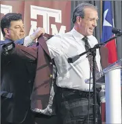  ?? DAVE MCDERMAND / COLLEGE STATION EAGLE ?? Texas A&M Athletic Director Scott Woodward helps coach Jimbo Fisher put on a maroon blazer Monday. Fisher cited his friendship with Woodward as one reason he took the job.