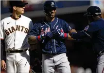  ?? The cycle Sunday with D. ROSS CAMERON/AP ?? Braves outfielder Eddie Rosario (center) celebrates with first base coach Eric Young Sr. after completing a ninthinnin­g single against the Giants in San Francisco.