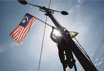  ?? BERNAMA PIC ?? A Port Dickson Municipal Council employee putting up the Jalur Gemilang in Port Dickson, Negri Sembilan, recently. The West should stop carrying a broad brush and pronouncin­g how this or that place does not measure up.