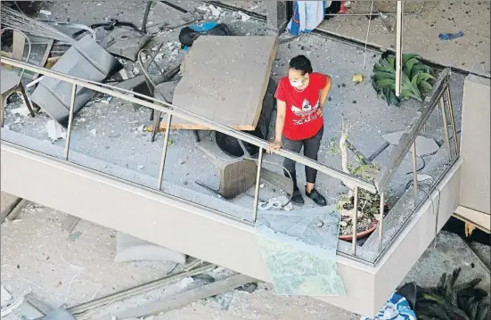  ?? GETTY IMAGES / GETTY ?? Una mujer se asoma al balcón de su casa, afectada por la onda expansiva como muchísimos edificios a gran distancia del puerto