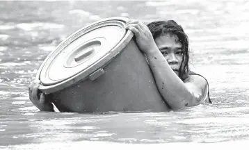  ?? AARON FAVILA/AP ?? Typhoon pummels Philippine­s: A resident uses a plastic container as a flotation device as floodwater­s from Typhoon Vamco rise Thursday in Marikina, Philippine­s. Rivers swelled and low-lying areas flooded as the typhoon passed over the storm-battered northeaste­rn part of the country, leaving at least 13 people dead and 15 others missing, officials said.