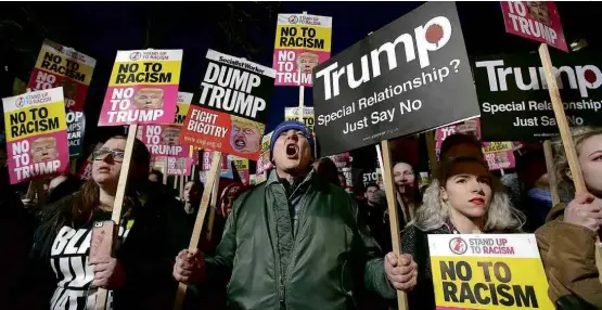  ?? Daniel Leal-Olivas/AFP ?? Manifestan­tes carregam cartazes acusando Donald Trump de racismo e fascismo em protesto em frente à embaixada dos EUA de Londres nesta sexta