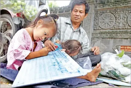  ?? HENG CHIVOAN ?? Eam Chhay teaching his daughter while selling guava on Preah Sihanouk Blvd in the capital’s Prampi Makara district.