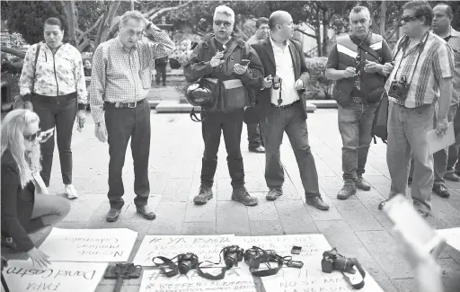  ?? — Gambar AFP ?? TUNTUT KEADILAN: Kamera diletakkan di atas kain rentang yang tertera mesej protes ketika para wartawan jurugambar mengadakan demonstras­i susulan kematian Castro di hadapan Istana Kerajaan di San Luis Potosi, kelmarin.