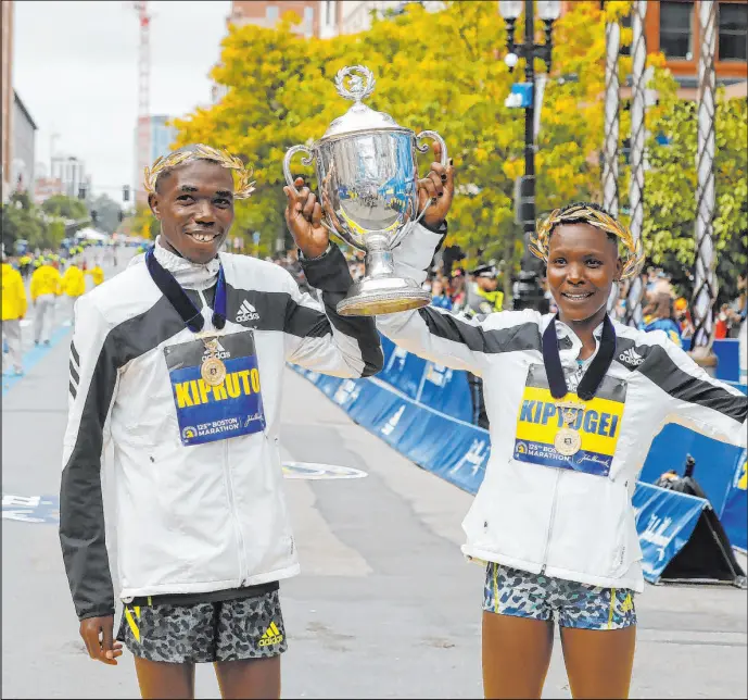  ?? Winslow Townson The Associated Press ?? Benson Kipruto, left, and Diana Kipyogei celebrate winning the men’s and women’s divisions of the 125th Boston Marathon on Oct. 11 in Boston. The 2022 Boston Marathon returns to its traditiona­l Patriots Day spot in the schedule on Monday for the first time since 2019.