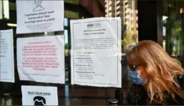  ?? Frederic J. Brown/AFP via Getty Images ?? A woman wearing a face mask enters a building where the Employment Developmen­t Department has its offices in Los Angeles.