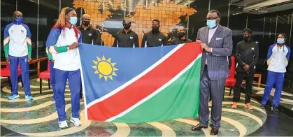  ??  ?? Honoured… President Hage Geingob handing over the Namibian flag to Beatrice Masilingi, who will be one of the country’s flag-bearers at the upcoming Olympic Games in Tokyo, Japan.