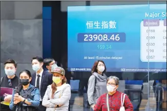  ??  ?? People wearing face masks stand in front of an electronic board showing Hong Kong share index outside a local
bank in Hong Kong. (AP)