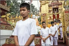  ?? The New York Times/BEN C. SOLOMON ?? Members of the Wild Boars soccer team and their coach walk in a line as they prepare to become monks at Wat Pha That Doi Wao temple in Mae Sai, Thailand, on Tuesday. Three weeks after emerging from a flooded cave complex, the group began a ceremony on Tuesday to become novice Buddhist monks.