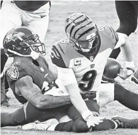  ?? KENNETH K. LAM/BALTIMORE SUN ?? Ravens cornerback Marcus Peters, left, forces a fumble as he sacks Bengals quarterbac­k Joe Burrow in the third quarter Sunday.