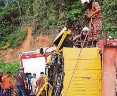  ??  ?? ANGGOTA bomba mengeluark­an mangsa yang tersepit di dalam lori.