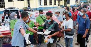  ??  ?? Helping hand: Zuraini (left) and other volunteers handing out free food to the needy at Jalan Tun Razak, Johor Baru.