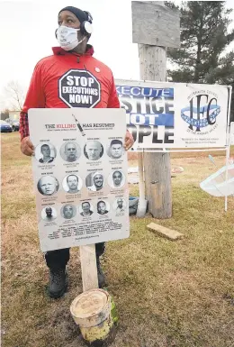  ?? JOSEPH C. GARZA /AP PHOTOS ?? ABOVE: Charles Keith, of Ohio, protests near the Federal Correction­al Complex in Terre Haute, Ind. — where Corey Johnson was executed Thursday. Keith holds a sign with mugshots of the 10 men and one woman who were executed by the federal government since July 14.
BELOW: Christina Bollo, of Illinois, joins the protest.