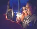  ??  ?? Nova Aguilar, center, and Savanna Molina, both 12, take part in a candleligh­t vigil for their friend Jeremiah Valencia in Nambé Wednesday night.