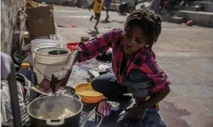  ?? Photograph: Odelyn Joseph/AP ?? A woman stirs a pot of food at the Hugo Chávez public square on 20 October.