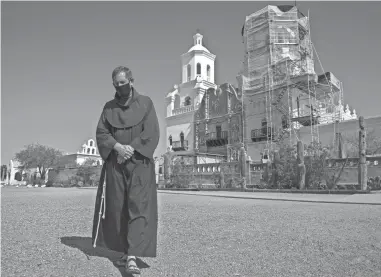  ?? BENJAMIN CHAMBERS/ARIZONA REPUBLIC ?? Father William Minkel walks outside San Xavier del Bac Mission in Tucson, Aug. 5.