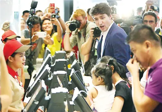  ??  ?? TRUDEAU STOPS FOR JOLLIBEE — Canadian Prime Minister Justin Trudeau makes a side-trip to a Jollibee store at North Harbour in Pasay City, ordering fried chicken and a strawberry float while greeting customers and posing for groufies shortly after he...