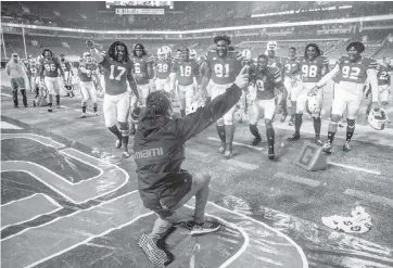  ?? AL DIAZ adiaz@miamiheral­d.com ?? UM coach Manny Diaz slides across a field tarp after the Hurricanes defeated the Virginia Cavaliers 19-14 on Oct. 24. The Hurricanes finished the 2020 season with an 8-2 record and ranked No. 18 in the final College Football Playoff poll.