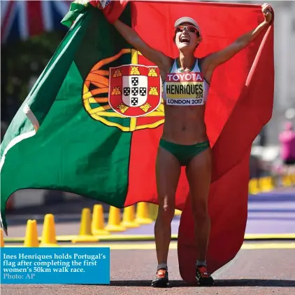  ??  ?? Ines Henriques holds Portugal’s flag after completing the first women’s 50km walk race. Photo: AP