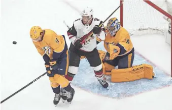  ?? JASON FRANSON/AP ?? The Coyotes' Carl Soderberg, middle, tries to screen Predators goalie Juuse Saros (74) as Dante Fabbro blocks the puck during the first period of Tuesday’s NHL qualifying round game.