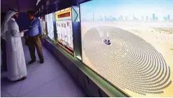  ??  ?? DUBAI: Visitors look at screens displaying images of the Mohammed bin Rashid AlMaktoum Solar Park yesterday, at the solar plant in Dubai.