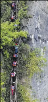 ?? CHINATOPIX VIA AP ?? The schoolchil­dren who must use a bamboo ladder for their more 2,500-foot climb might soon get a set of steel stairs.