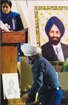  ?? (AP/Ross D. Franklin) ?? Rana Singh Sodhi, brother of Balbir Singh Sodhi, moves a portrait of his brother Wednesday at a memorial service on the 20th anniversar­y of the murder of Balbir Singh Sodhi in Mesa, Ariz.