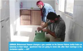  ?? — AFP ?? AMMAN: Mohammed Hassan changes a gas canister as his fiancee Rahme Jaafar looks on Saturday in their future apartment that are going to move into after their marriage in the Jordanian capital.