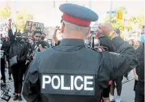  ?? CHRIS YOUNG THE CANADIAN PRESS ?? A police officer throws up a fist as protesters march in an anti-racism rally in Toronto on June 6.