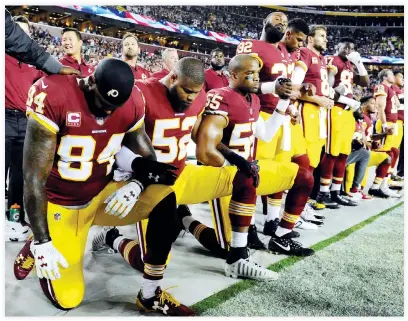  ??  ?? Washington Redskins tight end Niles Paul (84) and linebacker Ryan Anderson (52) and Washington Redskins linebacker Chris Carter (55) kneel with teammates during the playing of the national anthem before the game between the Washington Redskins and the...