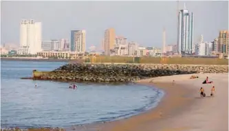  ??  ?? KUWAIT: A Kuwaiti woman walks past a sign reading in Arabic: “for your safety swimming and fishing are temporaril­y banned” at a beach in Kuwait City yesterday. An oil spill was discovered recently off the Kuwaiti coast, and pollution was also detected...