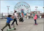  ?? PTI ?? Youngsters ride scooters pass the Wonder Wheel ride as they celebrate the Memorial Day weekend on the boardwalk at Coney Island during the current Coronaviru­s outbreak in New York