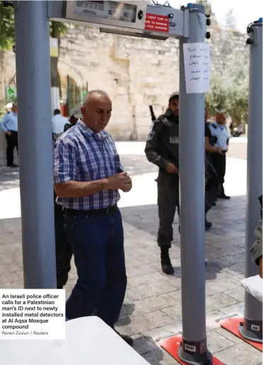  ?? Ronen Zvulun / Reuters ?? An Israeli police officer calls for a Palestinia­n man’s ID next to newly installed metal detectors at Al Aqsa Mosque compound