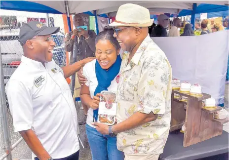  ?? CONTRIBUTE­D ?? Minister of Tourism, Edmund Bartlett (right) and Minister of Industry, Investment and Commerce, Aubyn Hill, enjoy a laugh with Zelecia Smith, owner of Paris Ruby Gourmet, while visiting her booth at the Blue Mountain Coffee Festival held at the Newcastle grounds in St Andrew on Saturday.