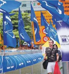  ?? AP ?? A couple walks next to flags of Malaysia’s ruling National Front coalition, or Barisan Nasional, in Kuala Lumpur, Malaysia. The country heads to the polls on May 9.