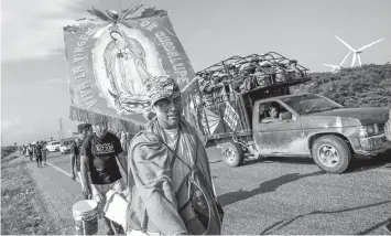  ?? ASSOCIATED PRESS ?? Erlin Troches, a 43-year-old Honduran migrant from the city of Santa Barbara, carries an image of the Virgin of Guadalupe that was given to him by a priest in southern Mexico, as he walks along with a thousands-strong caravan of Central Americans hoping to reach the U.S. border moves, outside Juchitan, Oaxaca state, Mexico.