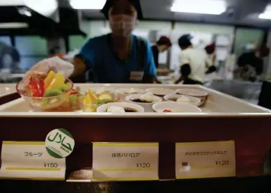  ??  ?? An employee shows a halal bowl of cut fruit at a dining hall in a university near Tokyo. The halal food industry has ballooned globally. (Reuters)