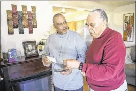 ?? JONATHAN NEWTON / WASHINGTON POST ?? Lawrence Lacks (right), 82, and Ron Lacks, 57, the son and grandson respective­ly of Henrietta Lacks, look at family photos in Baltimore, Maryland, on March 22. The two are at odds with other family members over Henrietta’s legacy. The HBO movie about...