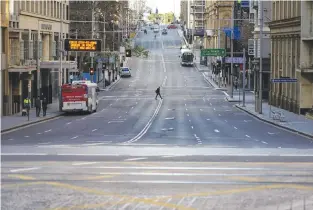  ?? (Loren Elliott/Reuters) ?? A PEDESTRIAN crosses an unusually quiet street in Sydney’s city center yesterday during a lockdown to curb the spread of COVID-19.