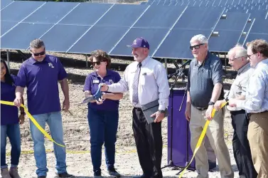  ?? The Sentinel-Record/Donald Cross ?? ■ Fountain Lake School District Superinten­dent Michael Murphy and school board President Dana Greeson hold the scissors during Monday’s ribbon-cutting ceremony for the new solar power plant, as solar modules are seen from behind.