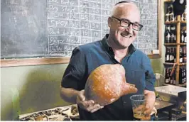  ?? SEBASTIAN SCHEINER/AP ?? Aren Maeir, an archaeolog­ist and professor at Bar Ilan University, holds an ancient jar and a glass of beer during Wednesday’s news conference in Jerusalem.