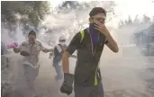  ?? AFP/GETTY IMAGES ?? Thai anti-government protesters run for cover from tear gas fired by riot police.