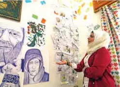  ??  ?? Syrian Cartoonist Amani Al-Ali speaks about some of her drawings at her home studio.