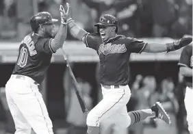  ?? THE ASSOCIATED PRESS ?? The Cleveland Indians’ Francisco Lindor, right, scores and is congratula­ted by Edwin Encarnacio­n during the 10th inning of their Tuesday game in Cleveland. The Indians won 2-1 on Lindor’s run.
